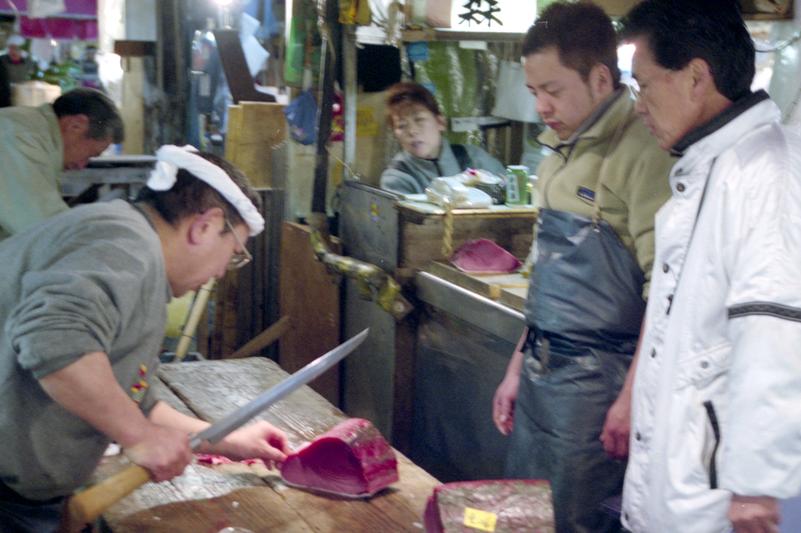 Un poissonnier prépare une pièce sous le regard attentif de son client.