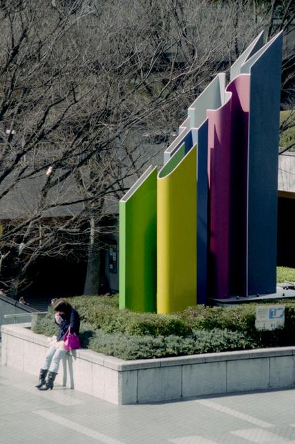 Une femme passe un coup de fil près d'une sculpture.